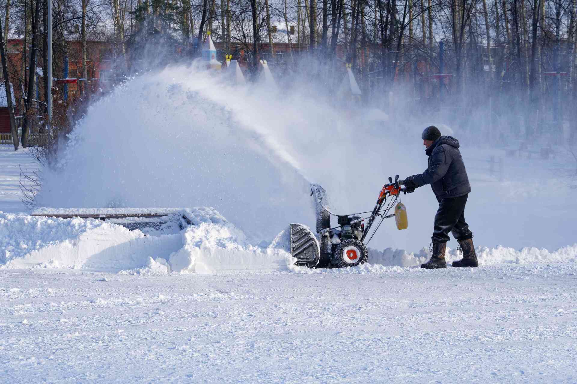 Operator running a snow blower that throws a plume of snow