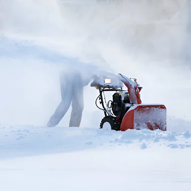 Snow blower clearing deep snow in bright daylight